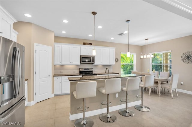 kitchen with a breakfast bar, white cabinets, and stainless steel appliances