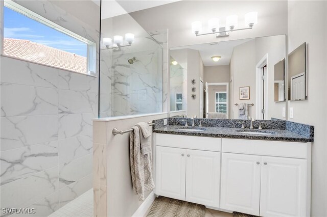 full bathroom featuring double vanity, a marble finish shower, and a sink