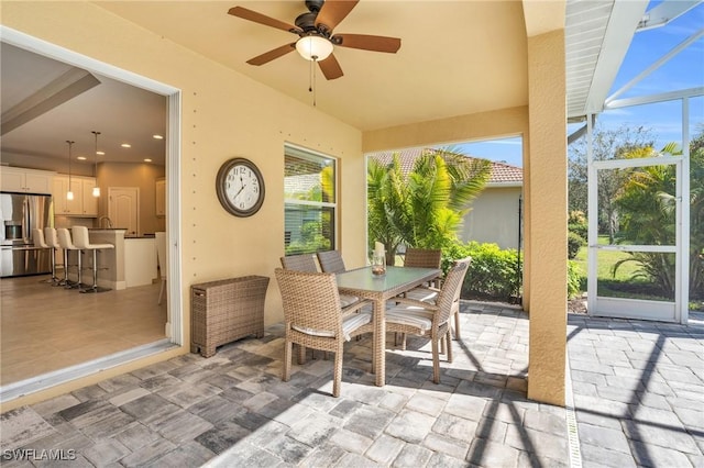 view of patio featuring a lanai, outdoor dining area, and ceiling fan