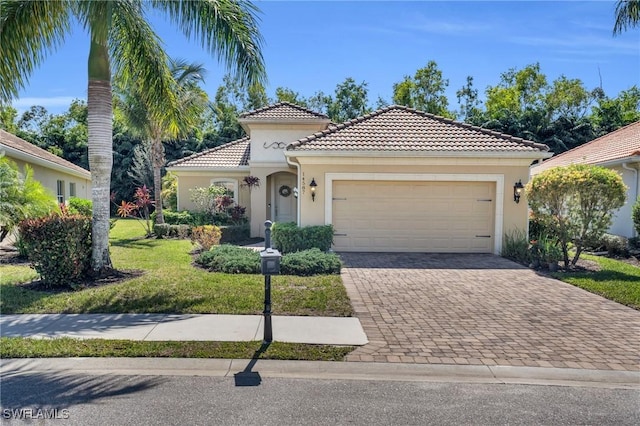 mediterranean / spanish house with a tiled roof, a front yard, stucco siding, decorative driveway, and an attached garage