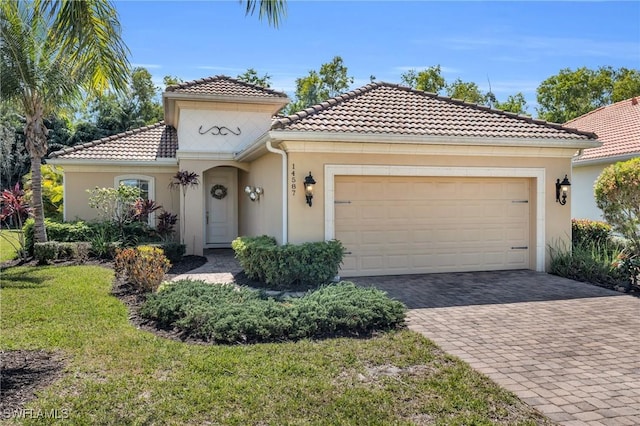 mediterranean / spanish house with stucco siding, decorative driveway, and a garage