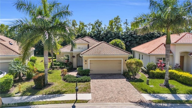 mediterranean / spanish home with decorative driveway, a garage, stucco siding, and a tile roof