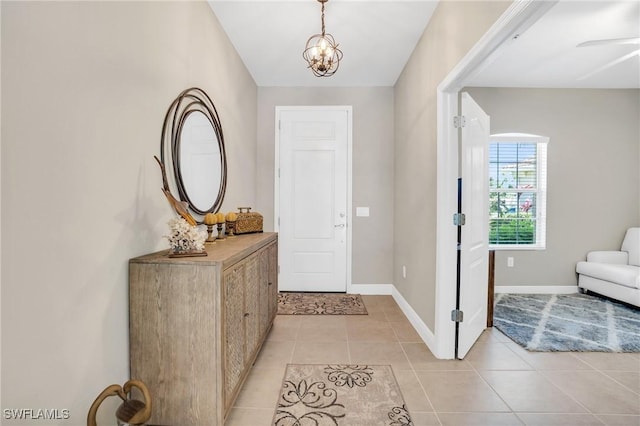 foyer entrance featuring a chandelier, baseboards, and light tile patterned flooring