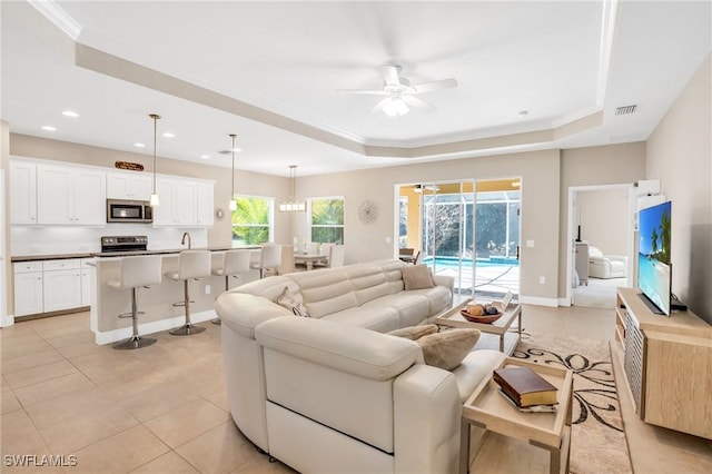 living area featuring visible vents, baseboards, a tray ceiling, recessed lighting, and a ceiling fan