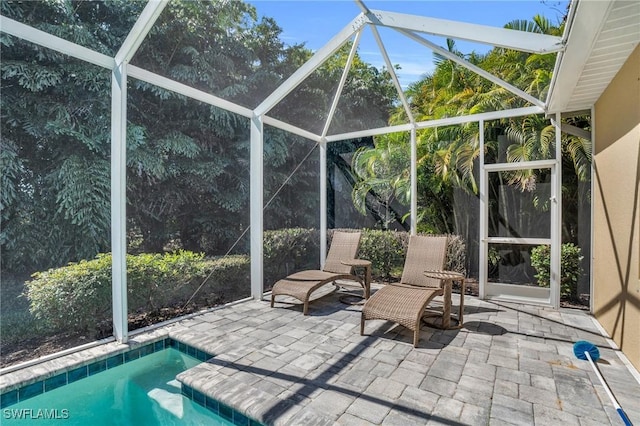 view of pool with glass enclosure and a patio