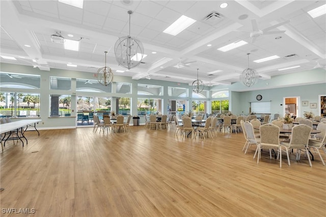 dining room featuring visible vents, light wood-type flooring, a high ceiling, an inviting chandelier, and coffered ceiling