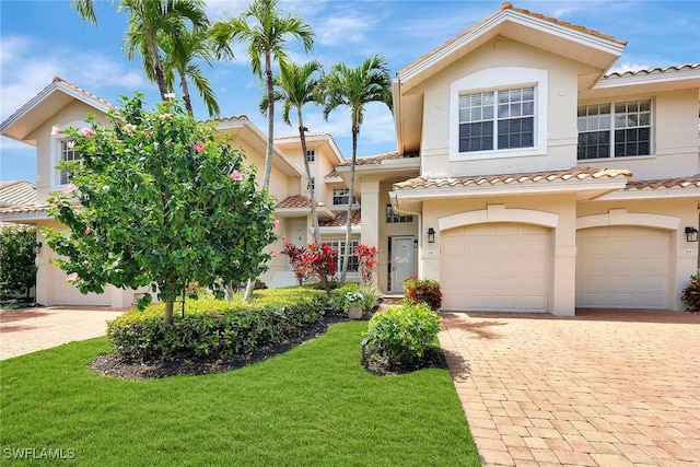 view of front of home featuring a garage, a front lawn, decorative driveway, and stucco siding