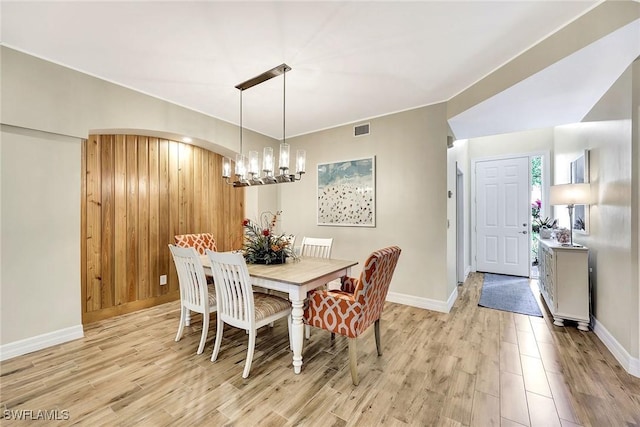 dining area featuring arched walkways, baseboards, visible vents, and light wood-style floors