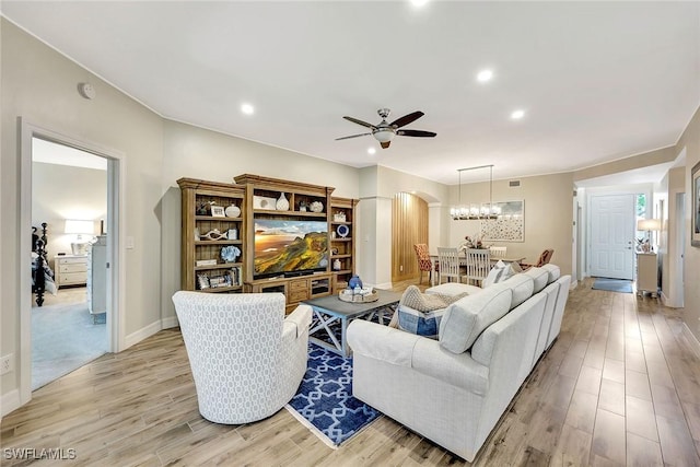 living area featuring arched walkways, light wood-type flooring, a ceiling fan, and baseboards