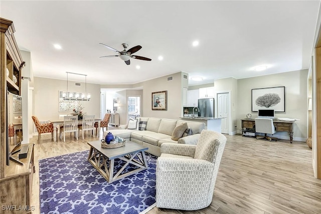 living room featuring light wood finished floors, ceiling fan, visible vents, and baseboards