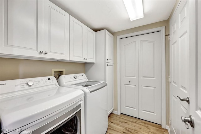 washroom with washer and dryer, cabinet space, and light wood-style flooring