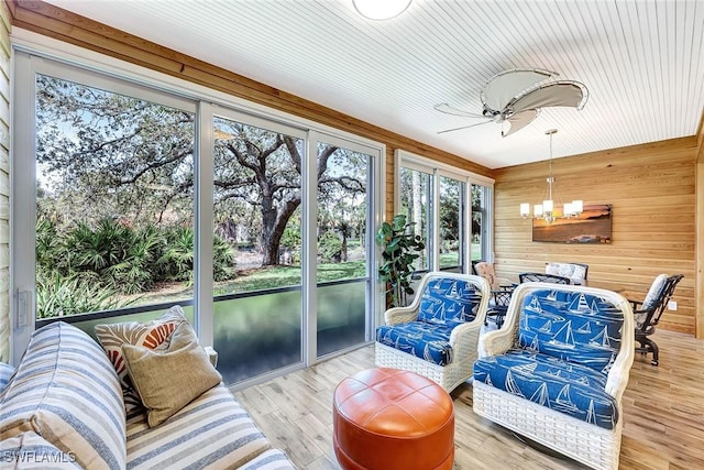 sunroom featuring ceiling fan with notable chandelier