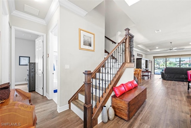 staircase featuring crown molding, visible vents, baseboards, and wood finished floors