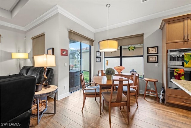 dining space with ornamental molding, light wood finished floors, and baseboards