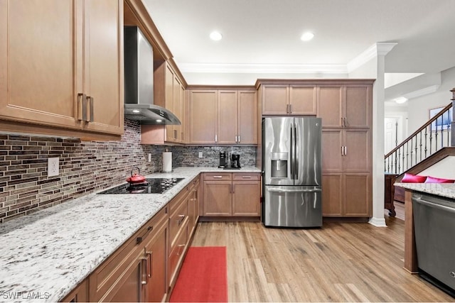 kitchen featuring light wood-style flooring, appliances with stainless steel finishes, wall chimney range hood, tasteful backsplash, and crown molding