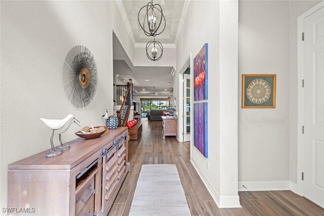 entryway featuring baseboards, crown molding, a chandelier, and wood finished floors