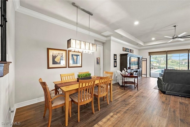 dining area featuring dark wood-style floors, crown molding, a raised ceiling, a ceiling fan, and baseboards