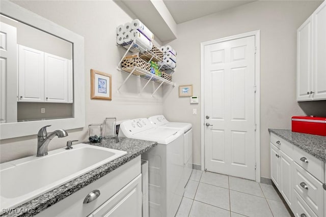 clothes washing area with light tile patterned floors, separate washer and dryer, a sink, baseboards, and cabinet space