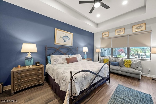 bedroom featuring a tray ceiling, recessed lighting, ceiling fan, wood finished floors, and baseboards