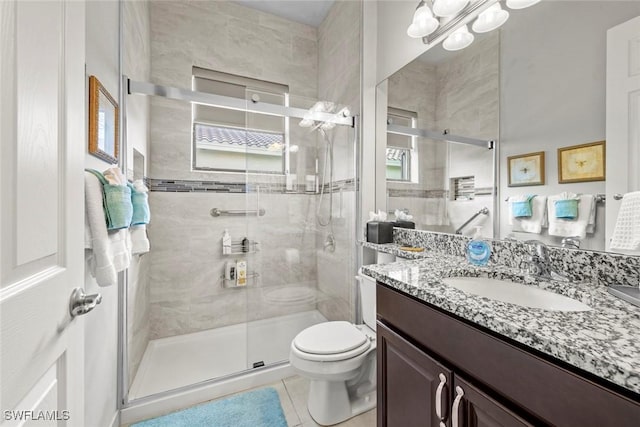 bathroom with vanity, a shower stall, toilet, and tile patterned floors