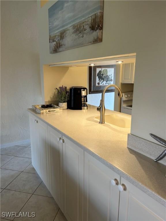 kitchen featuring white cabinetry, light countertops, light tile patterned floors, and a sink