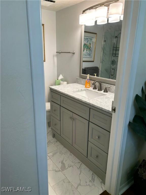 bathroom featuring vanity, marble finish floor, and a stall shower