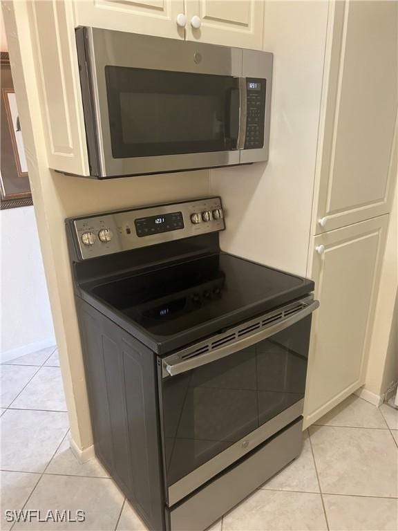 room details with baseboards, appliances with stainless steel finishes, and white cabinets