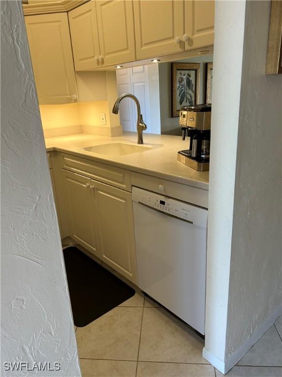 kitchen with a sink, dishwasher, light countertops, and light tile patterned floors