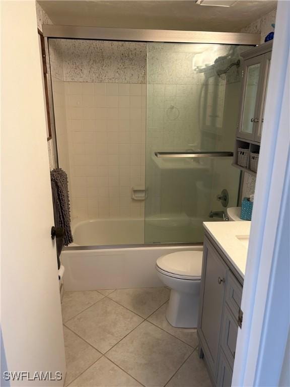 full bathroom featuring tile patterned floors, combined bath / shower with glass door, toilet, and vanity