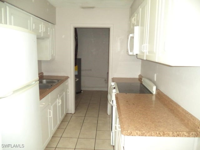 kitchen featuring light tile patterned floors, white appliances, a sink, and white cabinets