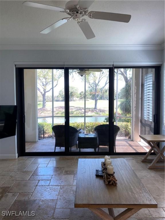 interior space with baseboards, ornamental molding, a water view, and stone tile floors