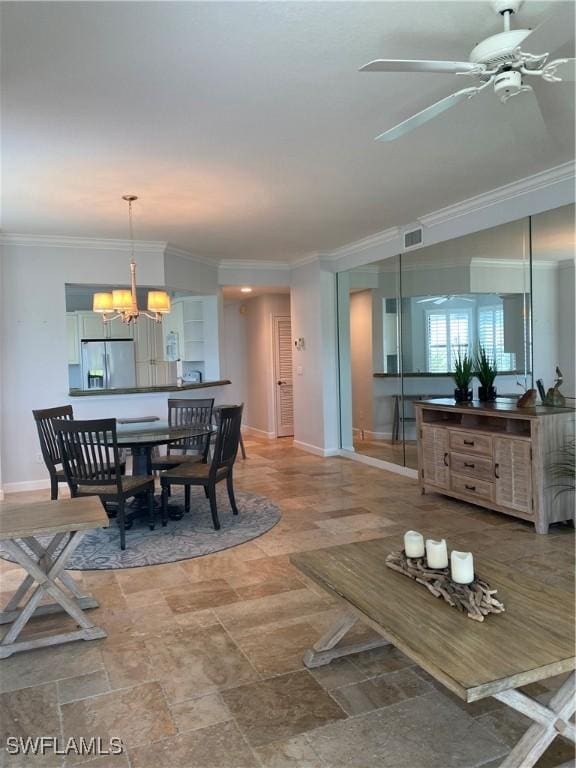 dining room featuring baseboards, visible vents, ornamental molding, stone finish flooring, and ceiling fan with notable chandelier