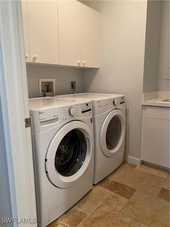 laundry room featuring cabinet space, stone tile floors, baseboards, and separate washer and dryer