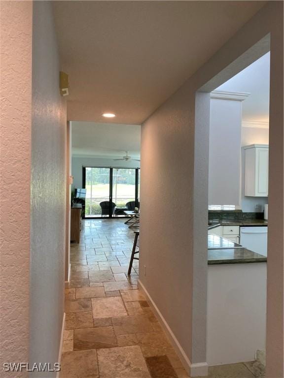 hall featuring stone tile flooring and baseboards