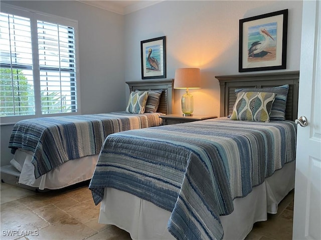 bedroom with ornamental molding and stone tile floors