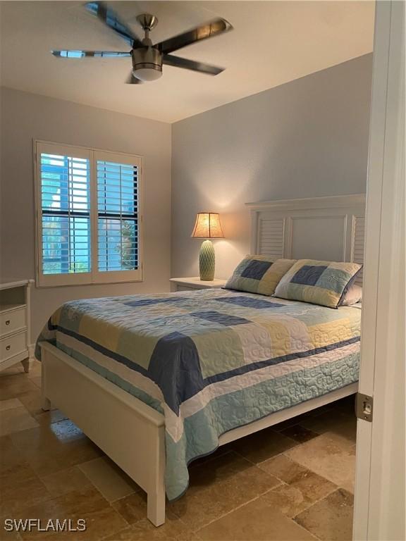 bedroom featuring ceiling fan and stone finish flooring