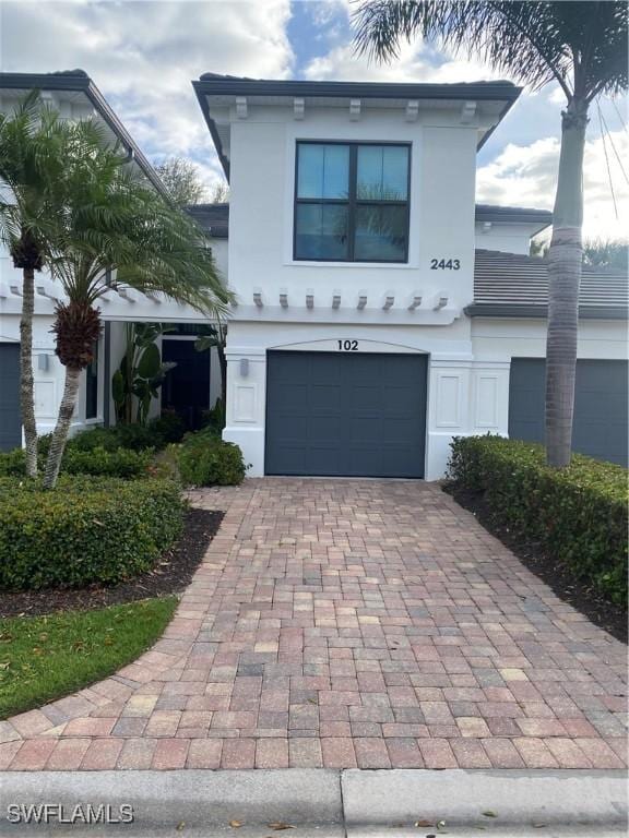 view of front of property with an attached garage, decorative driveway, and stucco siding