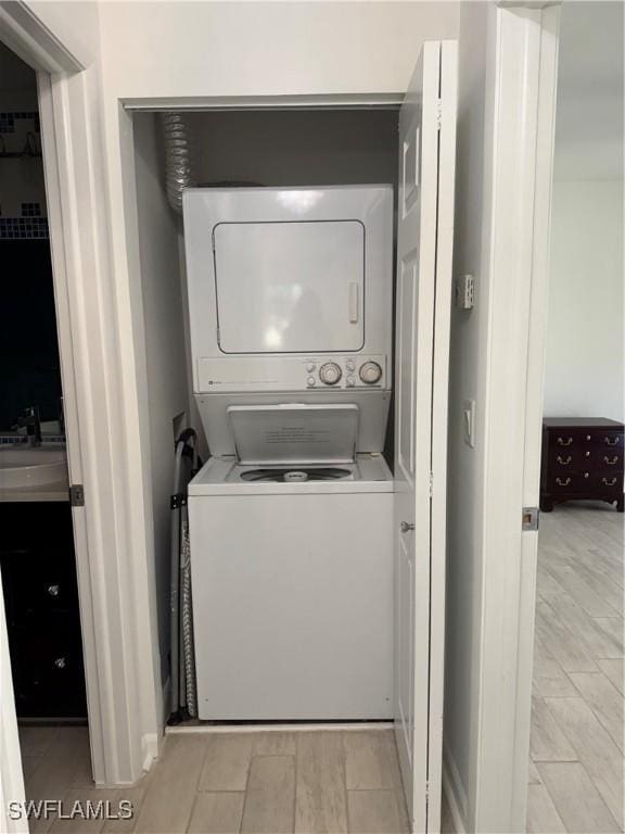 laundry room with stacked washer / dryer, laundry area, and a sink