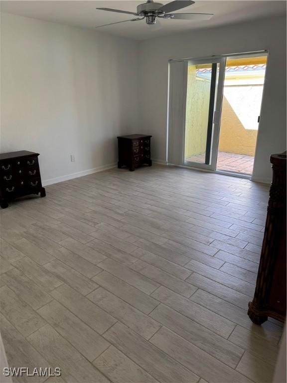 interior space with wood finished floors, a ceiling fan, and baseboards