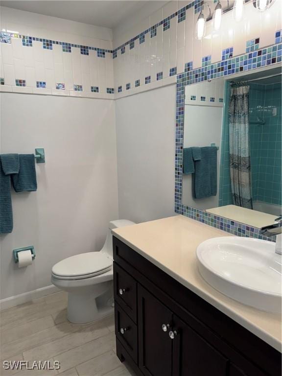 bathroom with curtained shower, decorative backsplash, toilet, vanity, and baseboards