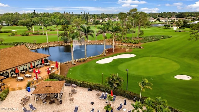 drone / aerial view with view of golf course and a water view