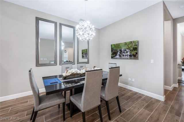 dining area with an inviting chandelier, wood tiled floor, and baseboards