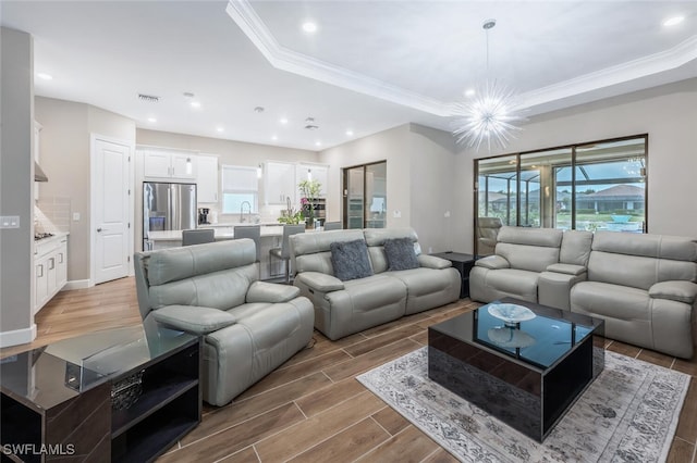 living area with recessed lighting, ornamental molding, a raised ceiling, and wood finish floors