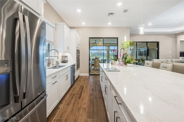 kitchen featuring appliances with stainless steel finishes, wood finish floors, a sink, and recessed lighting