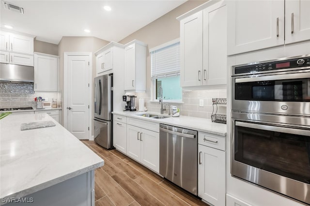 kitchen with under cabinet range hood, wood finish floors, a sink, visible vents, and appliances with stainless steel finishes