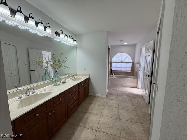 bathroom with double vanity, a garden tub, a sink, and tile patterned floors