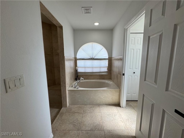 bathroom with tile patterned flooring, tiled shower, visible vents, and a bath