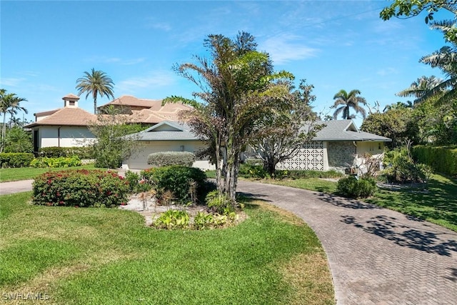 view of front of home featuring an attached garage, decorative driveway, and a front yard