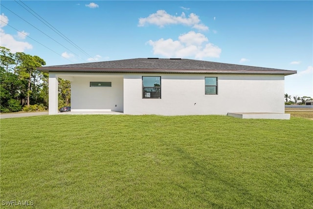 rear view of house featuring a patio, a lawn, and stucco siding