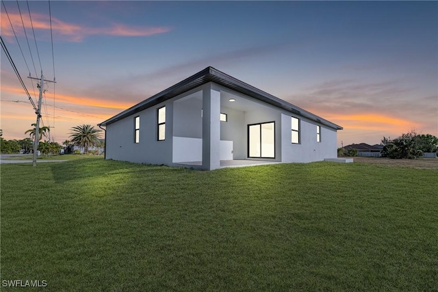 back of house with a lawn and stucco siding